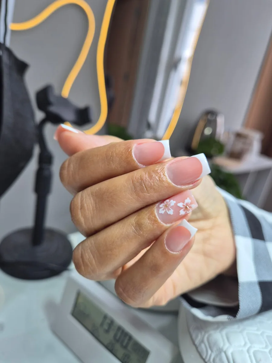Unhas com francesinha branca e detalhe floral